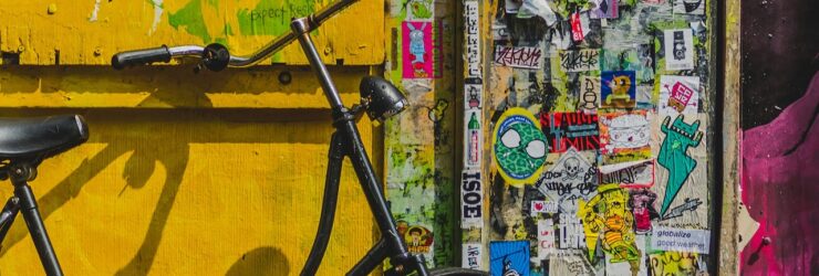 Bike parked beside wall full of stickers